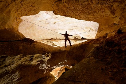 Grotte de Saint-Marcel d'Ardèche (puits Raoul) - Spéléo traversant une arche avec corde au dessus du puits Raoul (SP-24-2506)